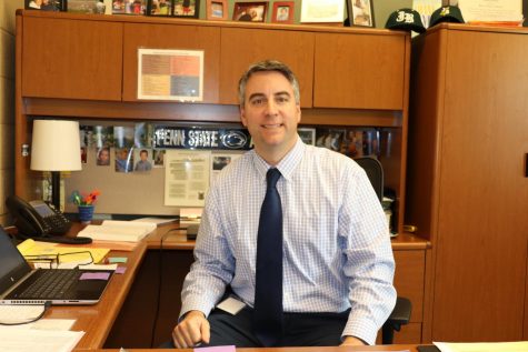 Mr. Thomas Bradley (Faculty) smiles for a photo at his desk.