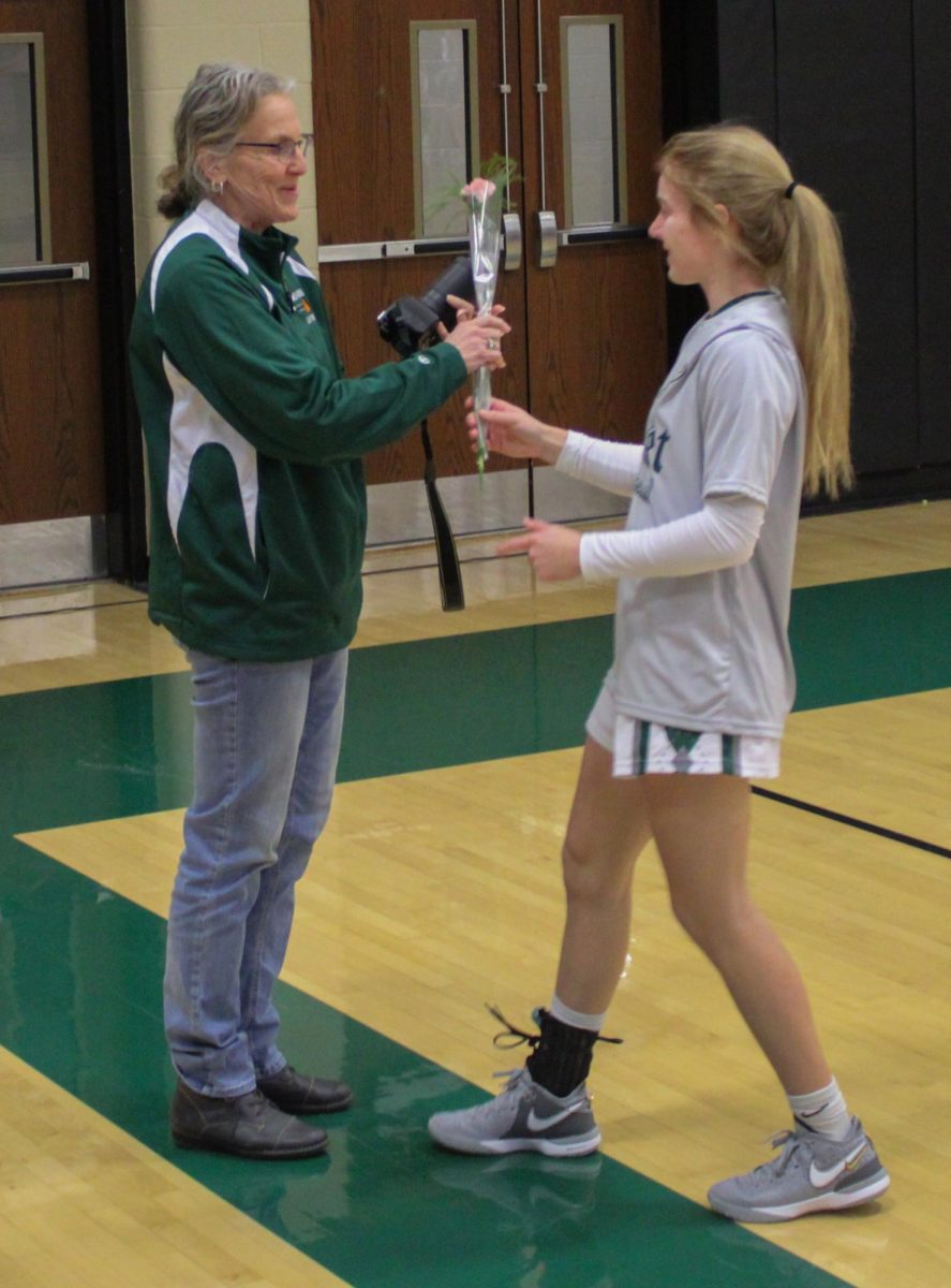 Honoring people afflicted by cancer, Grace Egli (12) hands a carnation to Jenny Lauthers, a cancer survivor. Every player on the James Buchanan High School girls basketball team gave out a carnation to a cancer patient. “It feels awesome to be honored,” Lauthers said.
