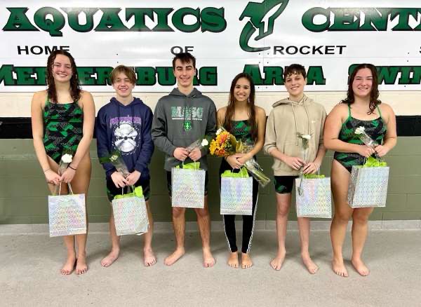 After receiving their flowers and gift bags, Line Feuillatre, Ethan Hopkins, William Dovey, Carissa Myers, Nicolas Ruiz, and Sofia Snider stand in front of the James Buchanan Aquatics banner for the last time together at a home competition. 